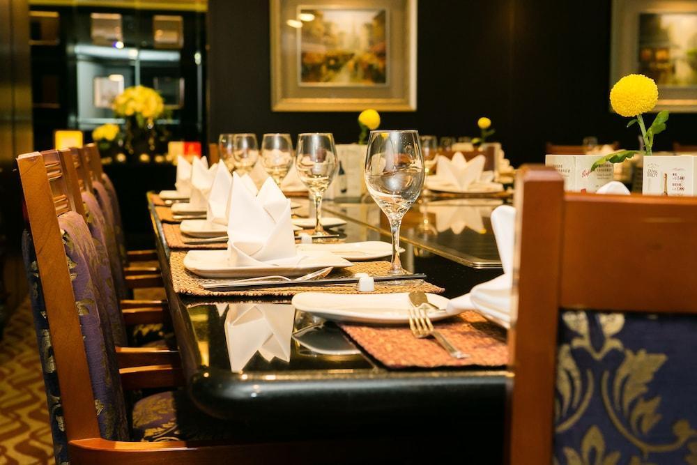 Evergreen Laurel Hotel - Taichung Esterno foto The photo depicts a dining table set for a formal meal. The table is long, covered with a dark tablecloth, and has neatly arranged plates, forks, and glasses at each setting. White napkins are folded elegantly, and there are small yellow flowers as c