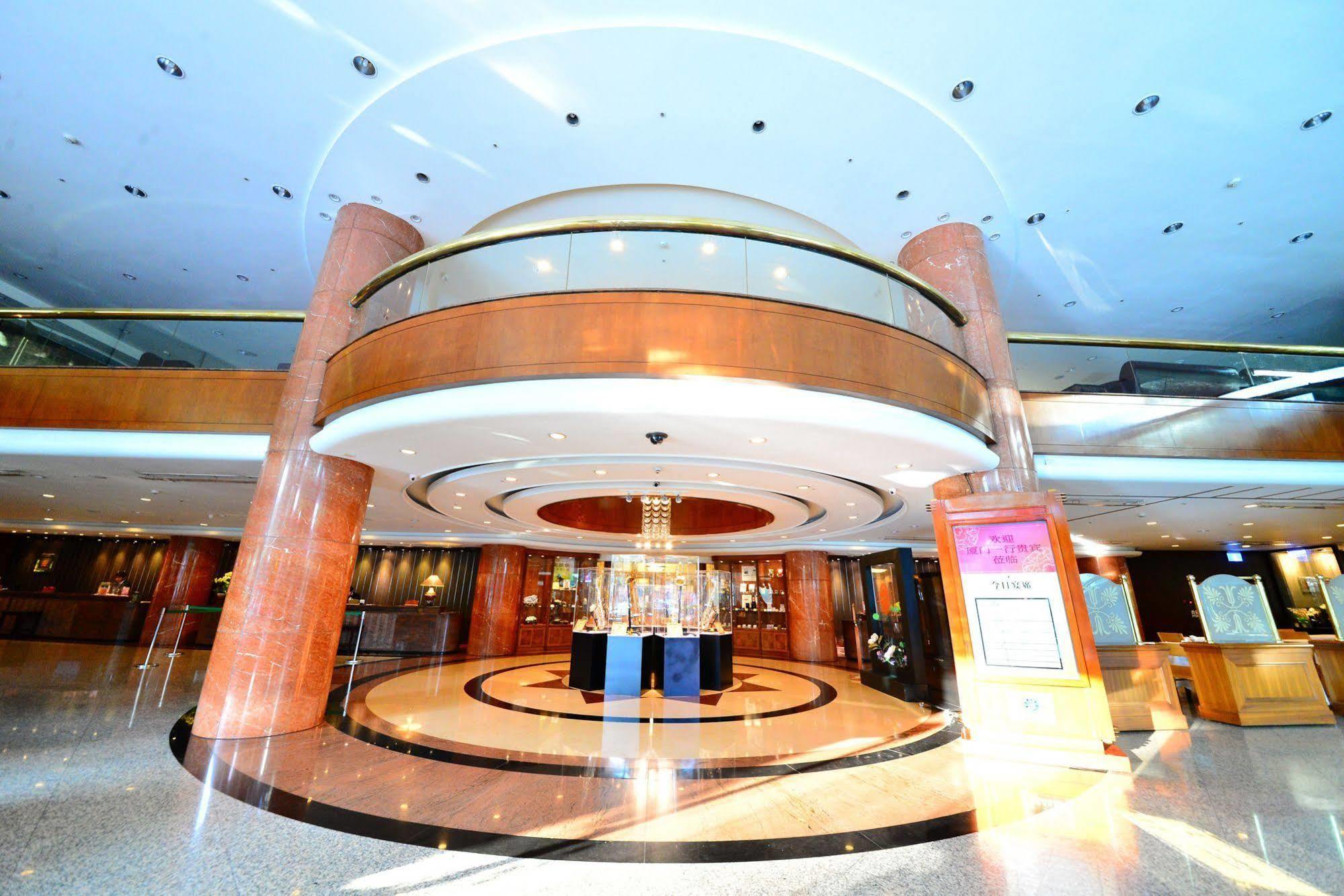Evergreen Laurel Hotel - Taichung Esterno foto The photo shows the interior of a spacious lobby area. It features a modern architectural design with polished surfaces and a circular ceiling structure. The walls are accented with wooden panels, and there is a central chandelier hanging from the ce