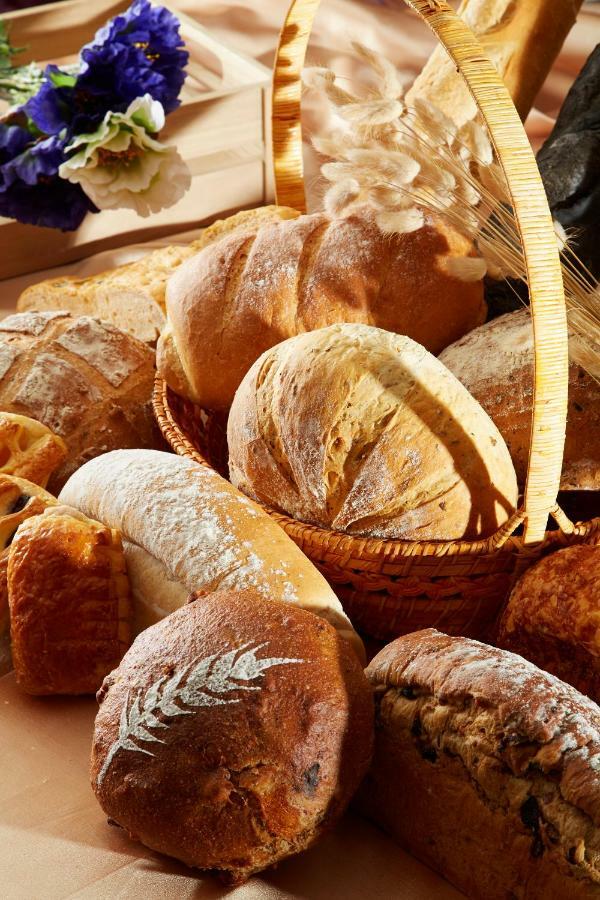 Evergreen Laurel Hotel - Taichung Esterno foto The photo shows a variety of freshly baked bread arranged in a woven basket. There are different types of bread, including round loaves, baguettes, and crusty rolls, showcasing a range of colors and textures. Some loaves have distinctive patterns or 
