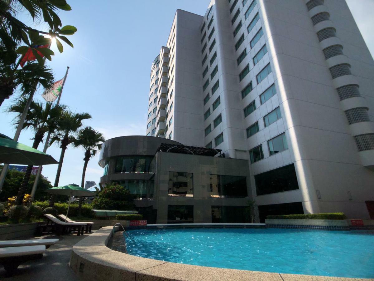 Evergreen Laurel Hotel - Taichung Esterno foto The photo depicts a hotel or residential building alongside a swimming pool. The pool is situated in the foreground, with a curved section of the building visible behind it. Surrounding the pool, there are lounge chairs for relaxation. In the backgro