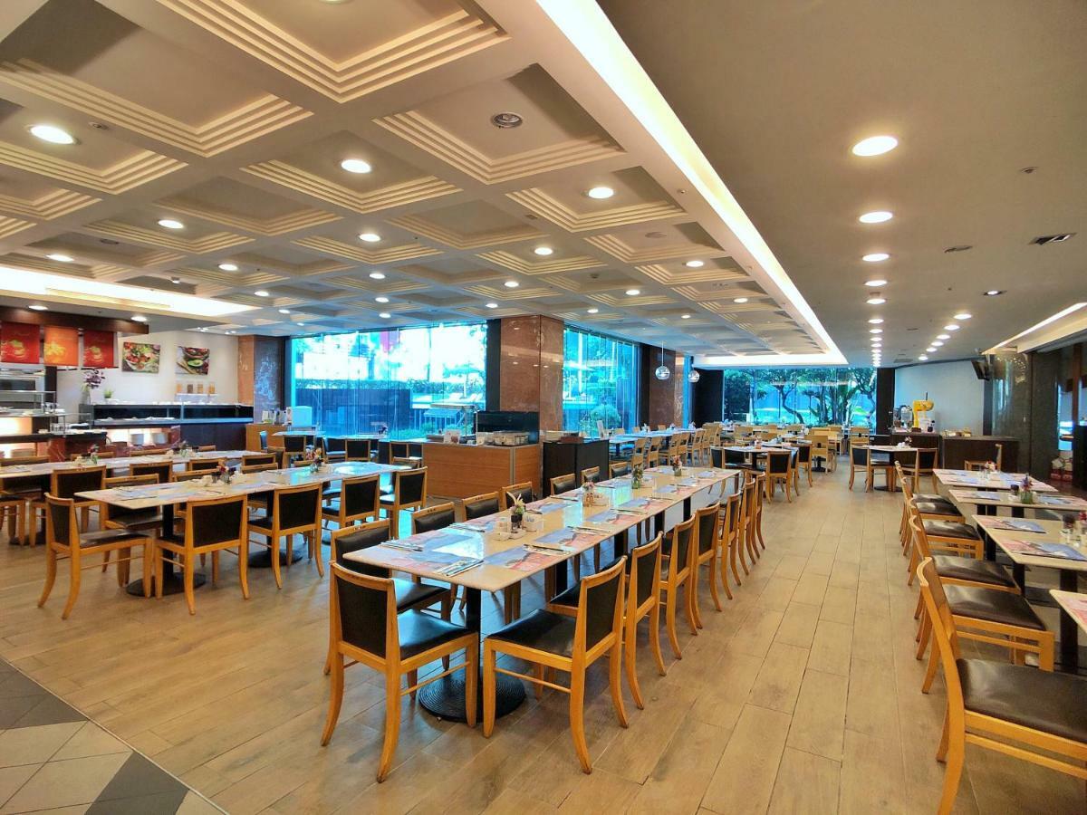 Evergreen Laurel Hotel - Taichung Esterno foto The photo shows the interior of a restaurant. It features a spacious dining area with several wooden tables and chairs arranged in rows. The floor has a light wood finish, complementing the stylish design. The ceiling is decorated with a modern patte